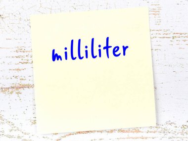 Tahta duvardaki sarı yapışkan notta el yazısıyla yazılmış mililitre.