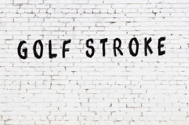 Yazılı beyaz tuğla duvar. Siyah boyayla yazılmış golf sopası.