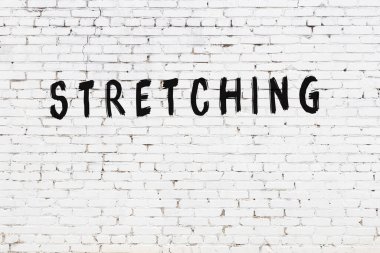 Siyah boyayla yazılmış el yazısı olan beyaz tuğlalı bir duvar.