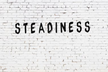 Üzerinde siyah boya bulunan beyaz tuğla bir duvar.