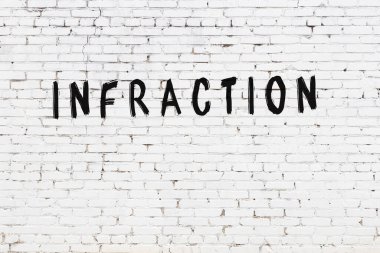 Siyah boyayla yazılmış beyaz tuğlalı bir duvar.