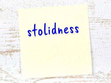 Ahşap duvardaki sarı yapışkan notta elle yazılmış kayıtsızlık var.