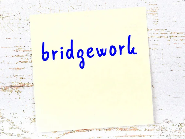 Tahta duvardaki sarı yapışkan notta el yazısıyla yazılmış köprü işi var.