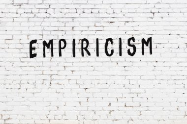 Siyah boyayla el yazısıyla yazması empirizm olan beyaz tuğla duvar.