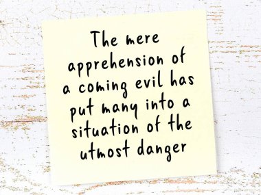 Sarı yapışkan not, ahşap duvarda el yazısıyla yazılmış zekice bir alıntıyla.