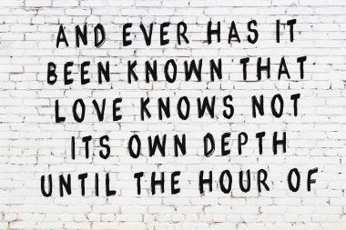 Beyaz tuğla duvar ve bilgece alıntıların yazılı olduğu siyah yazı.