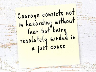 Tahta duvarda asılı sarı yapışkan nota elle yazılmış bilgece bir alıntı.