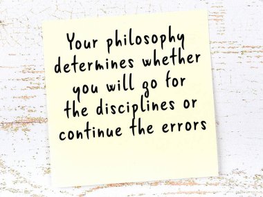 Tahta duvarda asılı sarı yapışkan nota elle yazılmış bilgece bir alıntı.