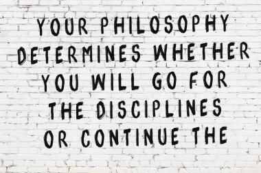 Beyaz tuğla duvara zekice alıntılar yazılı siyah bir yazı.