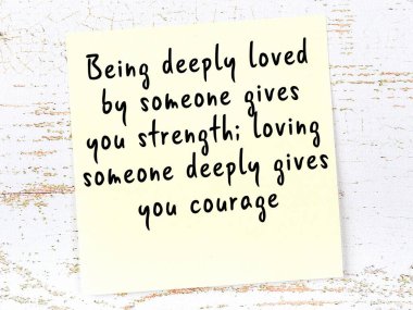 Tahta duvarda asılı sarı yapışkan nota elle yazılmış bilgece bir alıntı.