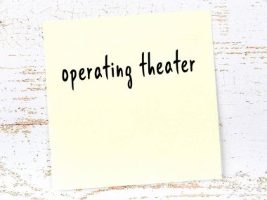 Ameliyathane hakkında hatırlatma. Tahta duvarda üzerinde yazı olan sarı yapışkan kağıt.