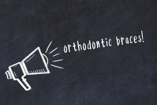 黒の机の上のスピーカーと手書きの碑文歯列ブレースのチョーク図面 — ストック写真