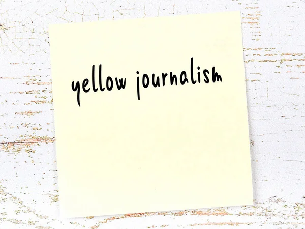 Concept of reminder about yellow journalism. Yellow sticky sheet of paper on wooden wall with inscription