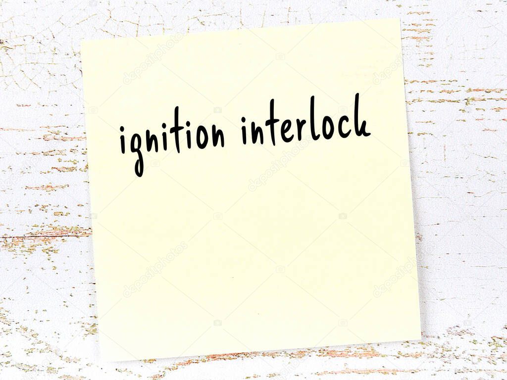 Concept of reminder about ignition interlock. Yellow sticky sheet of paper on wooden wall with inscription