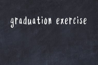 Tebeşir el yazısıyla yazılmış mezuniyet egzersizi siyah masada.