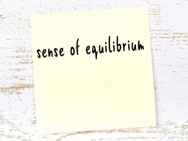 Denge duygusunu hatırlatma kavramı. Tahta duvarda üzerinde yazı olan sarı yapışkan kağıt.