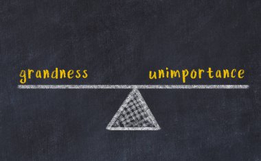 Büyüklük ve önemsizlik arasındaki denge kavramı. Üzerinde pullar ve kelimeler olan siyah bir karatahta.