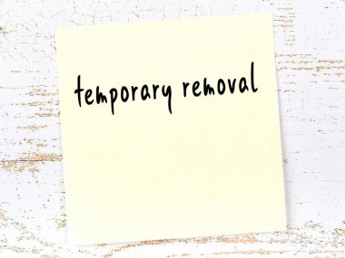 Ahşap duvardaki sarı yapışkan notta elle yazılmış yazılar geçici olarak kaldırılıyor.