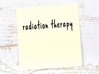 Tahta duvardaki sarı yapışkan notta el yazısıyla yazılmış radyasyon terapisi.