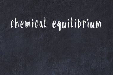 Üzerinde el yazısıyla yazılmış kimyasal denge olan üniversite yazı tahtası.