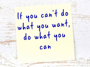 Tahta duvarda el yazısı motivasyon alıntısı olan sarı yapışkan not