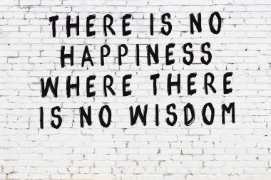 Beyaz tuğla duvara zekice alıntılar yazılı siyah bir yazı.