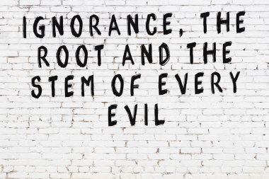 Beyaz tuğla duvara zekice alıntılar yazılı siyah bir yazı.