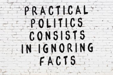 Beyaz tuğla duvara zekice alıntılar yazılı siyah bir yazı.