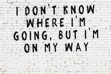 Beyaz tuğla duvara zekice alıntılar yazılı siyah bir yazı.