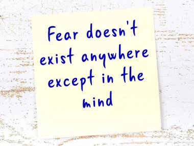 Sarı yapışkan not, ahşap duvarda el yazısıyla yazılmış zekice bir alıntıyla.