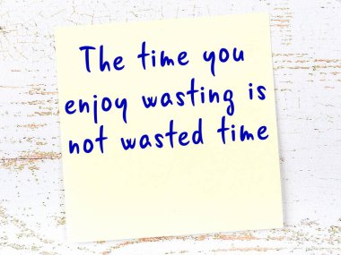 Tahta duvarda el yazısı motivasyon alıntısı olan sarı yapışkan not