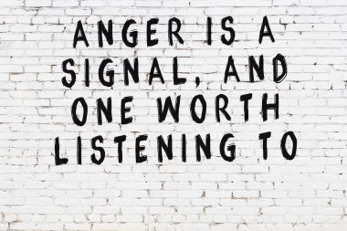 Beyaz tuğla duvar ve bilgece alıntıların yazılı olduğu siyah yazı.