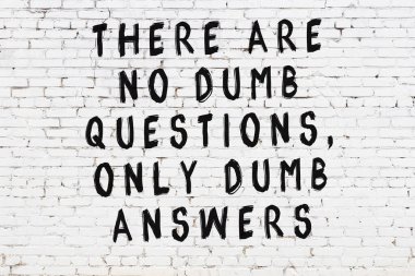 Beyaz tuğla duvara zekice alıntılar yazılı siyah bir yazı.