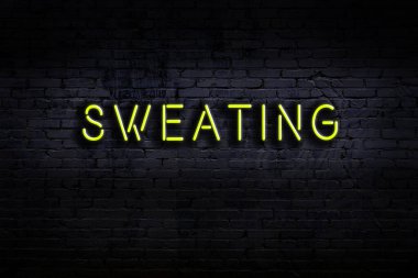 Üzerinde yazı olan neon levhası tuğla duvara yapışmış terliyor. Gece görünümü