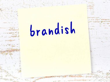 Tahta duvardaki sarı yapışkan notta el yazısıyla yazılmış brandish.