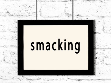 Üzerinde yazı olan siyah ahşap çerçeve beyaz tuğla duvarda asılı duruyor. 