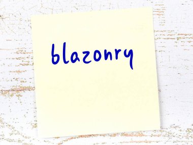 Tahta duvardaki sarı yapışkan notta el yazısıyla yazılmış blazoneri var.