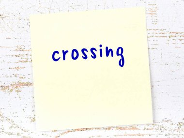 Karşıya geçmeyi hatırlatma kavramı. Tahta duvarda üzerinde yazı olan sarı yapışkan kağıt.