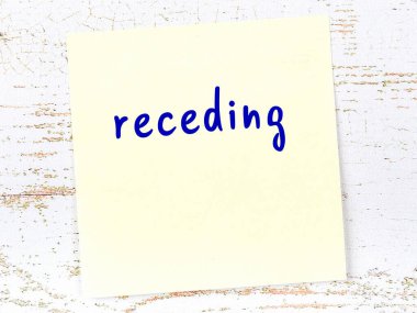 Tahta duvardaki sarı yapışkan notta el yazısıyla yazılmış yazı geri çekiliyor.