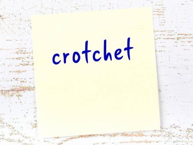 Tahta duvardaki sarı yapışkan notta el yazısıyla yazılmış crotchet.