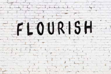 Yazı, beyaz tuğla duvara siyah boya ile yazılmış..