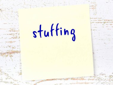 Tahta duvarda el yazısıyla yazılmış sarı yapışkan bir not var.