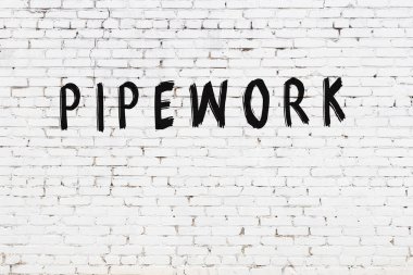 Beyaz tuğla duvarda siyah boyayla yazılmış yazıt borusu..