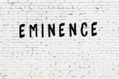 Beyaz tuğlalı duvar. Üstünlük yazılı. Siyah boyalı.