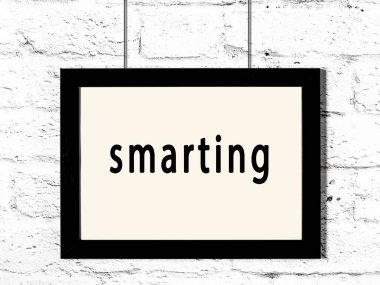 Üzerinde yazı olan siyah ahşap çerçeve beyaz tuğla duvarda asılı. 