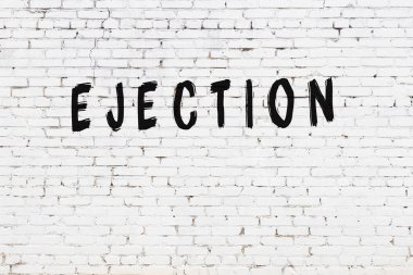 Siyah boyayla yazılmış beyaz tuğlalı bir duvar.