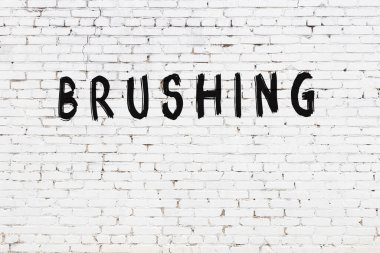 Beyaz tuğla duvarda siyah boyayla yazılmış yazı fırçası.