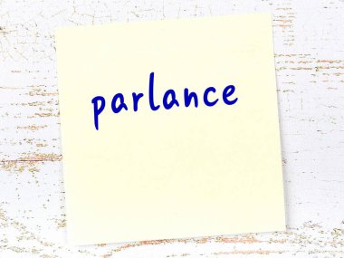 Tahta duvarda el yazısıyla yazılmış sarı yapışkan bir not.