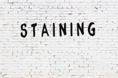 Üzerinde siyah boya olan beyaz tuğla bir duvar.