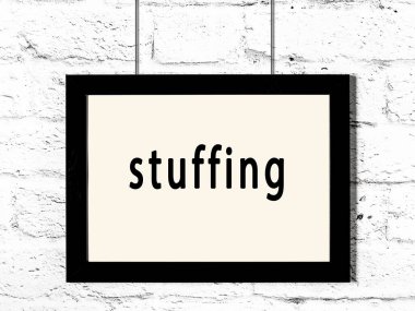 Siyah ahşap çerçeve, beyaz tuğla duvara yazı malzemesi asılmış. 